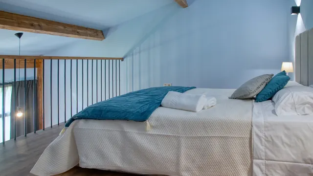 Quarto no mezanino com cama de casal e manta azul-petróleo