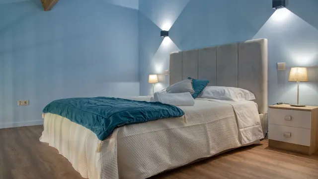 Quarto de casal com cabeceira estofada e candeeiros de parede