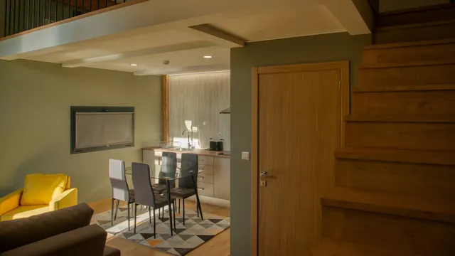 Sala de jantar com cadeirão amarelo e escada de madeira