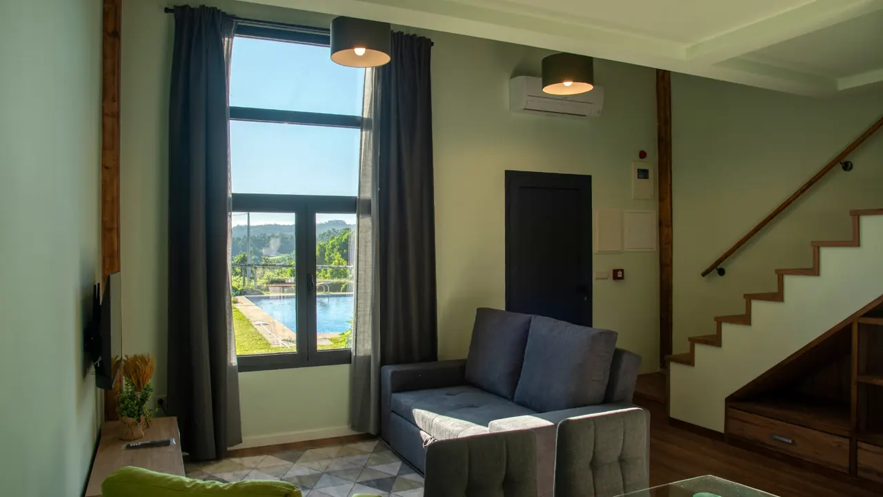 Sala com janela alta virada para a piscina e escada para o mezanino