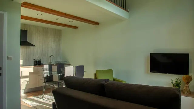 Sala com sofá, cadeirão verde e cozinha ao fundo